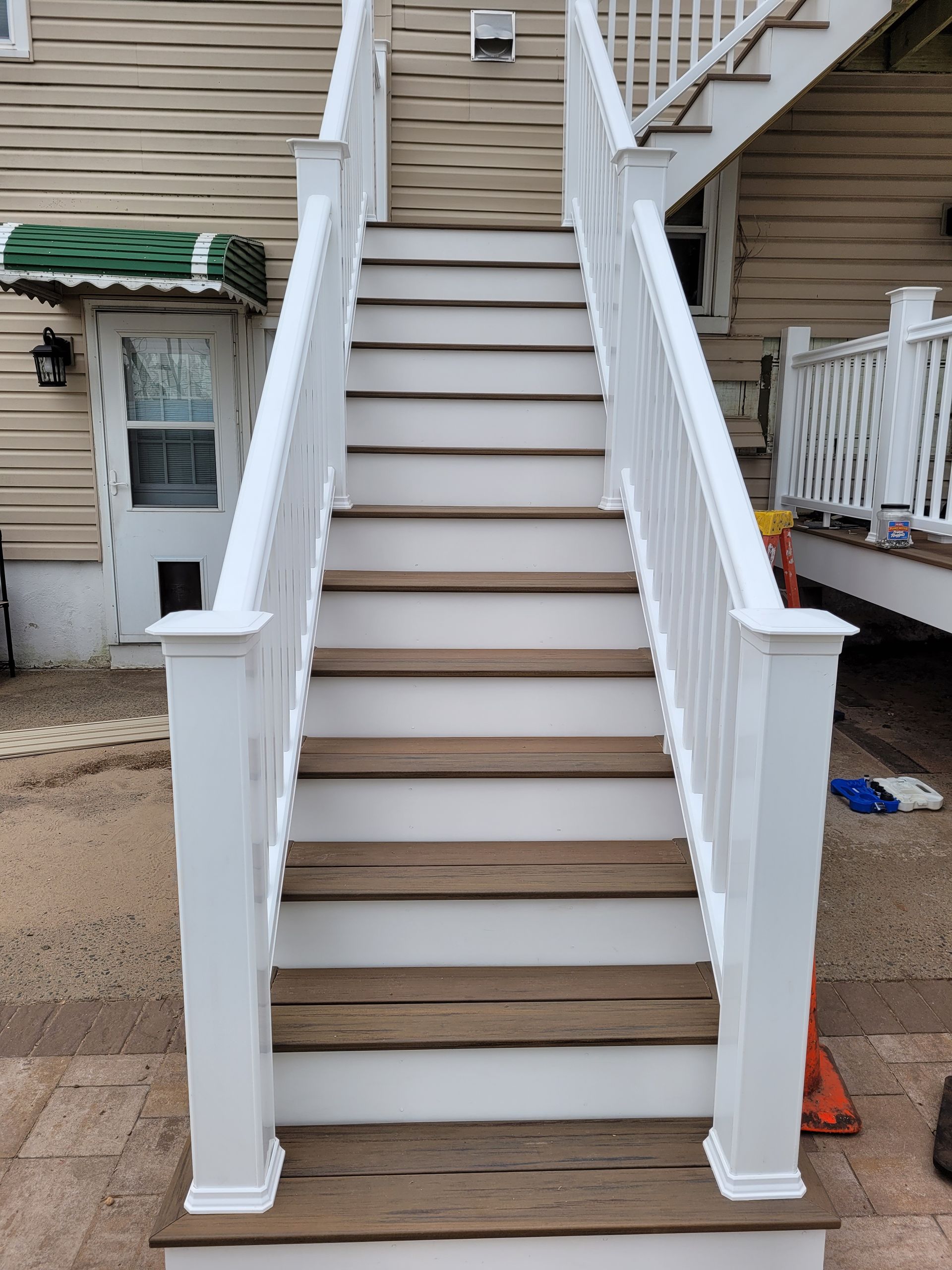 A set of stairs with wooden steps and a white railing leading up to a house.