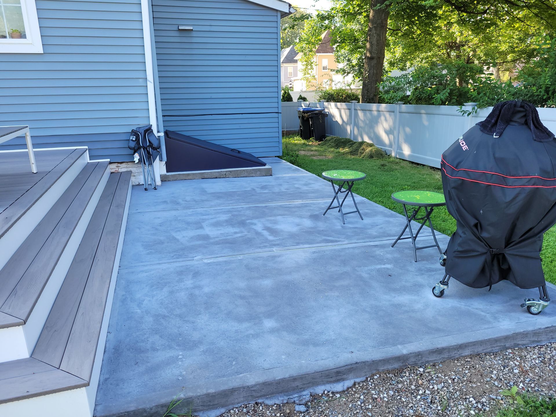 A patio with a grill and a table in front of a house
