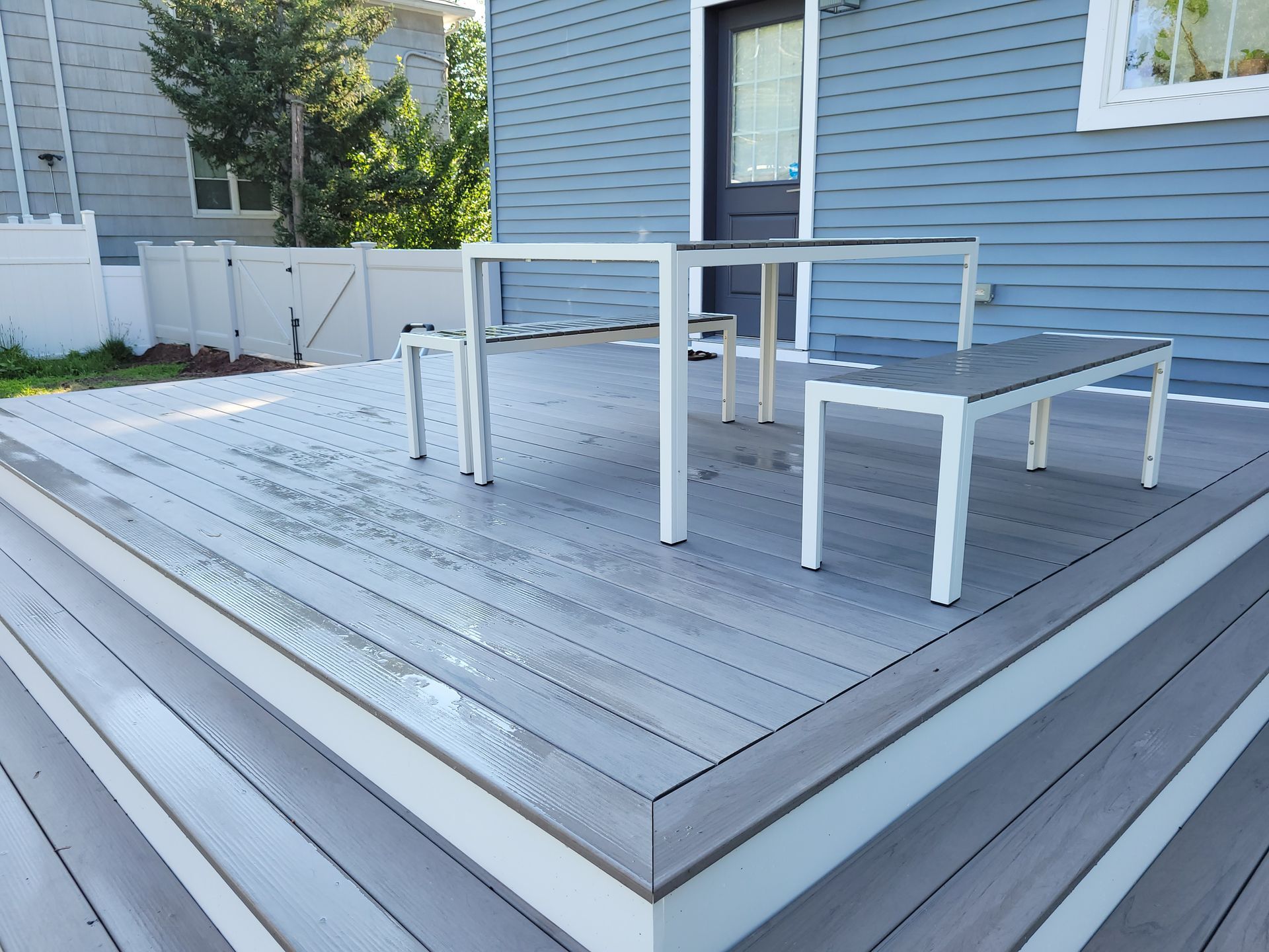 A wooden deck with a table and benches on it