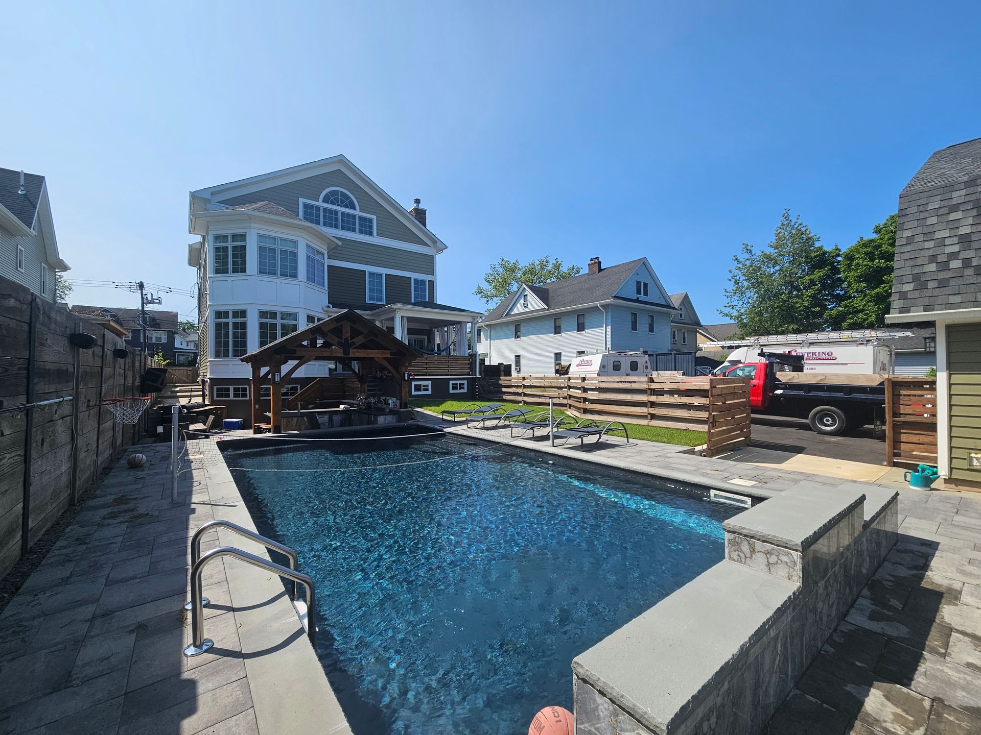A large swimming pool is in the backyard of a house.
