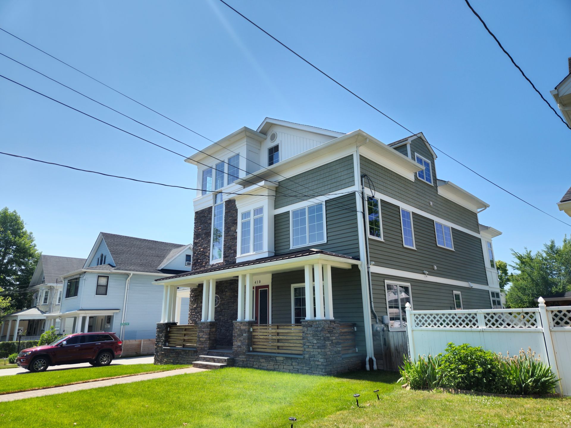 A large house with a car parked in front of it on a sunny day.