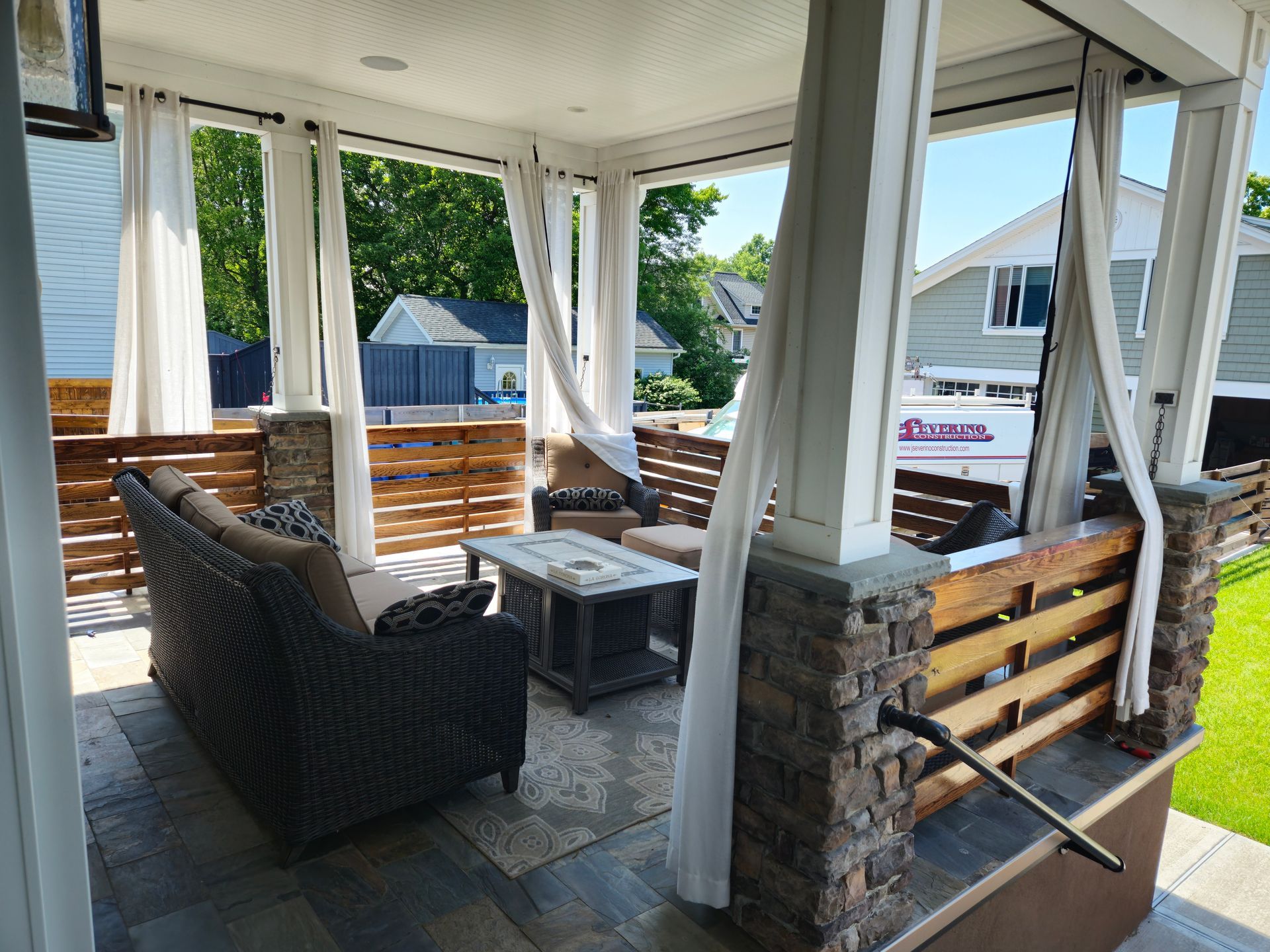 A porch with a couch , chairs , a table and a bench.
