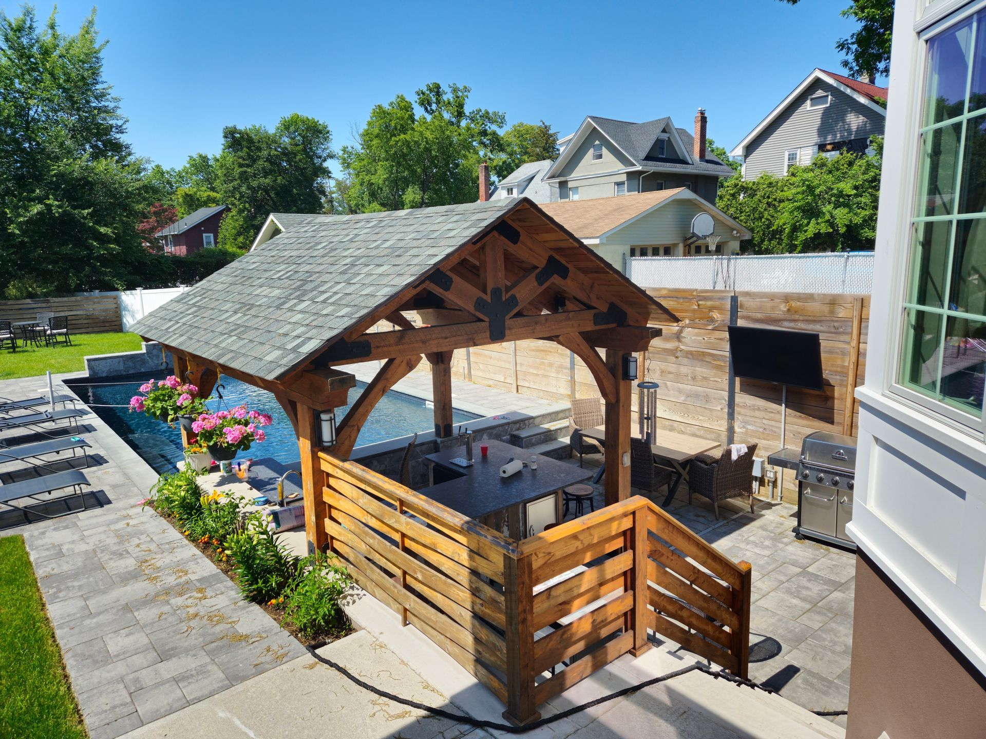 A wooden gazebo is sitting next to a pool in a backyard.