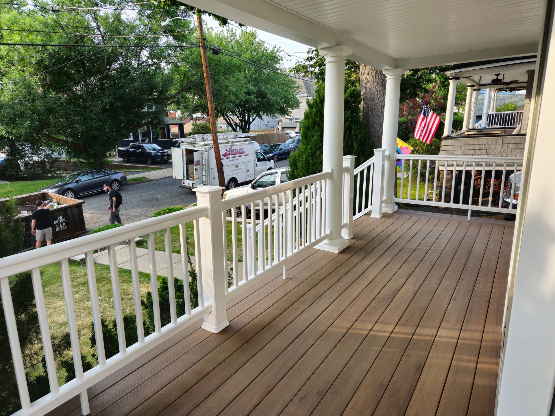 A porch with a white railing and a red white and blue american flag.