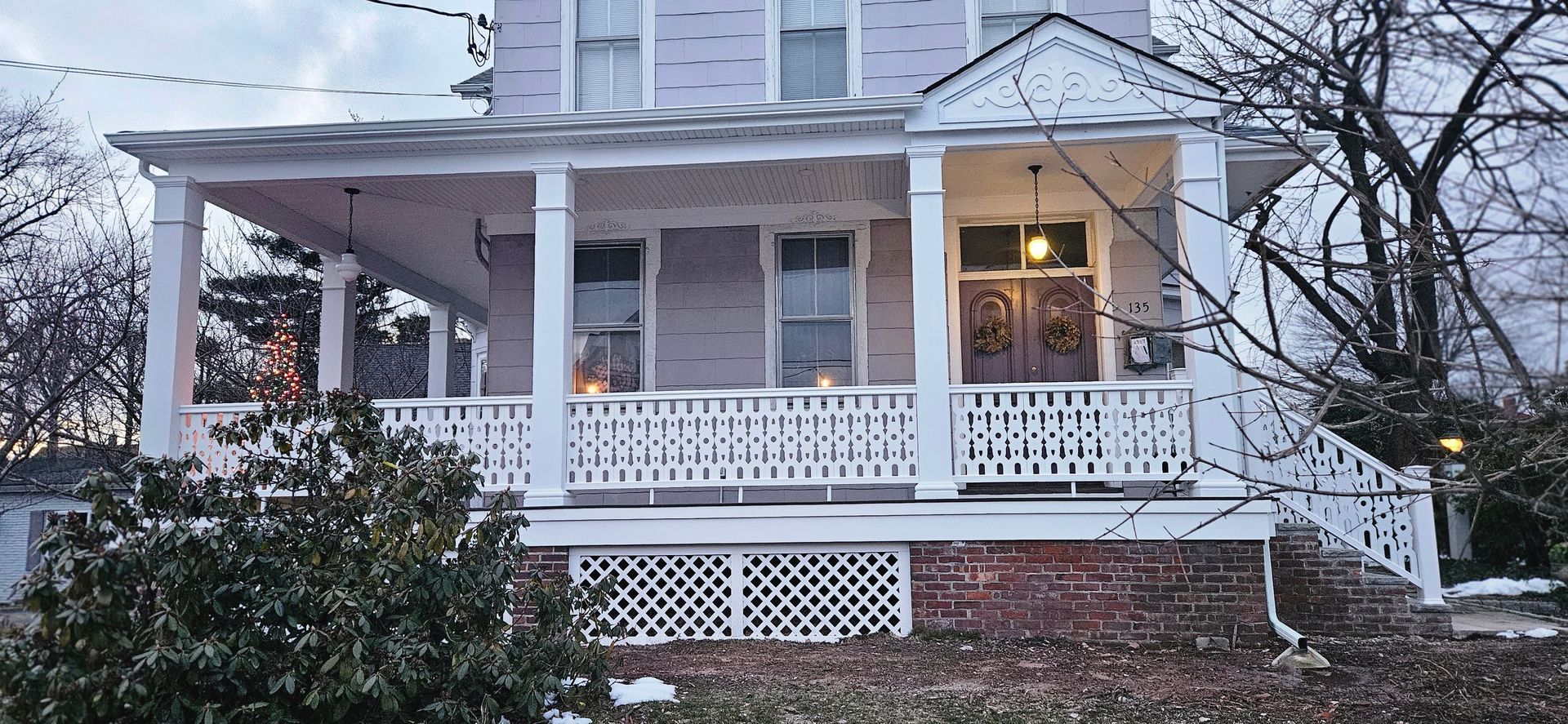 A large white house with a large porch and stairs.