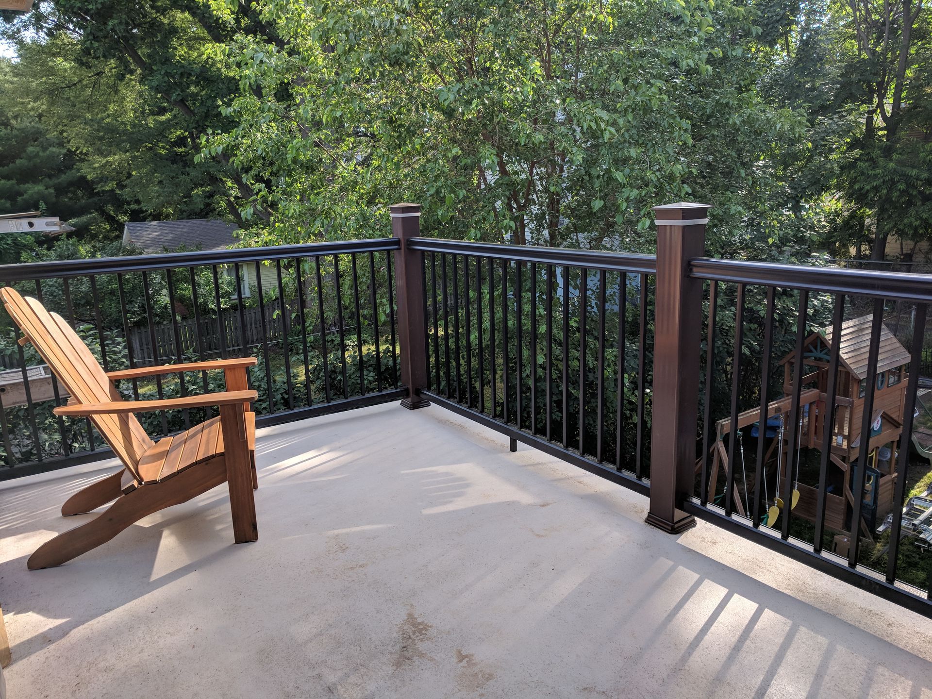 A wooden chair is sitting on a balcony with a metal railing.