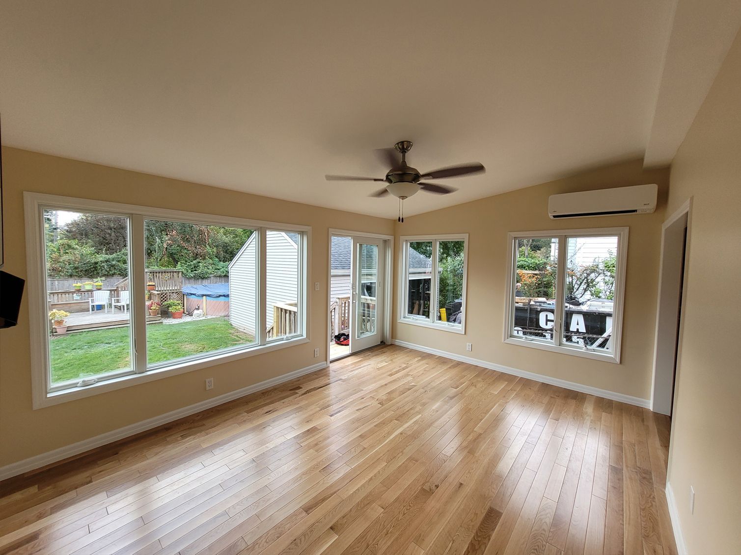 An empty living room with hardwood floors and a ceiling fan.