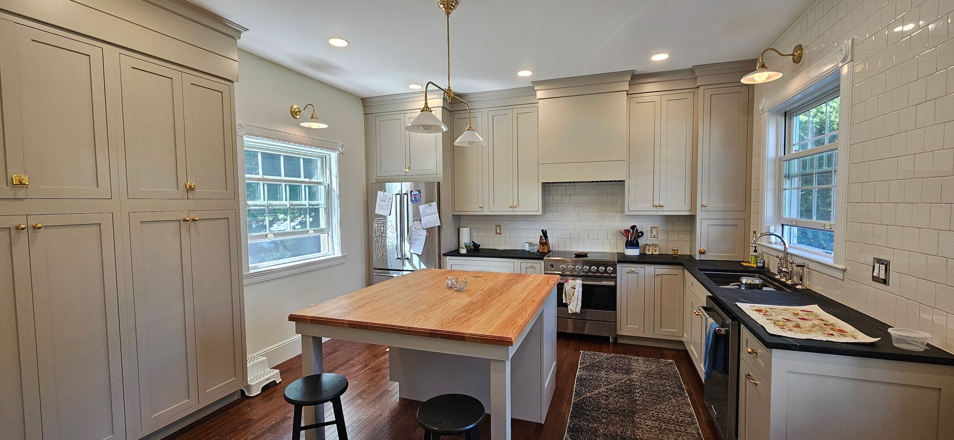 Kitchen with wood island, light cabinets, black countertops, and dark floor.