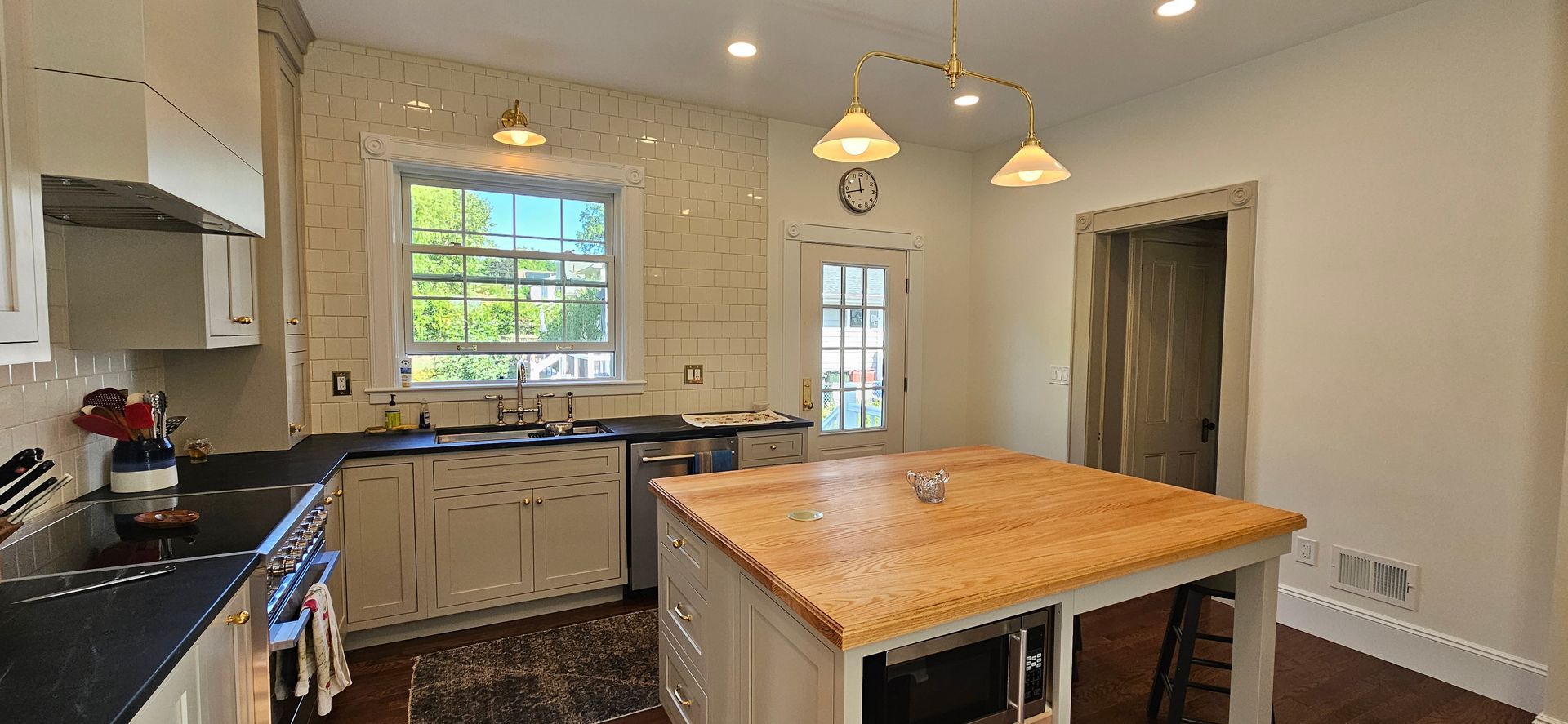 Kitchen with white cabinets, black countertops, and wooden island.