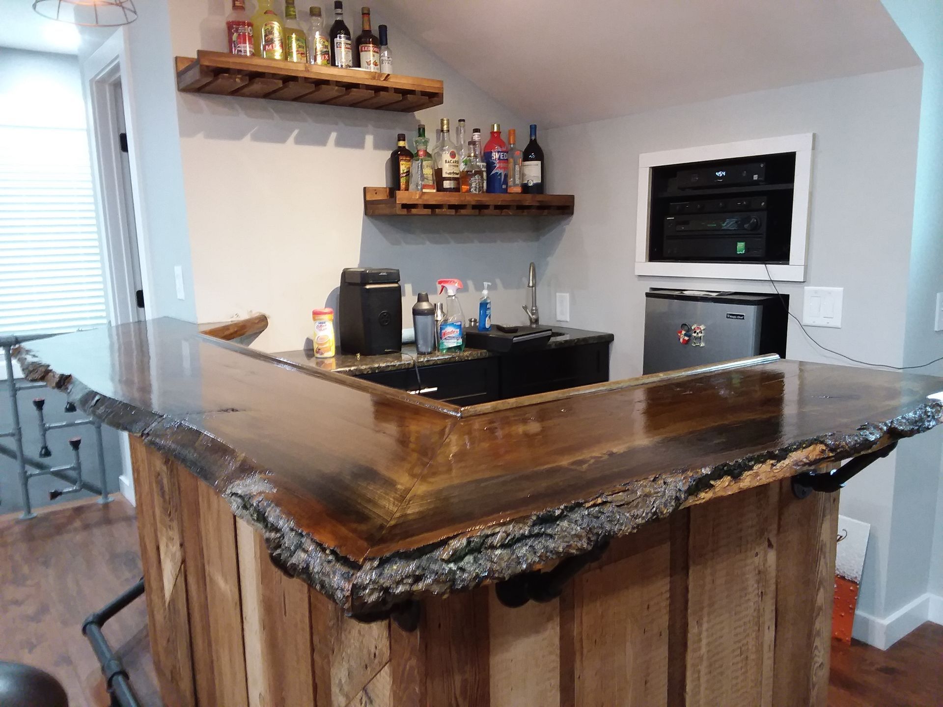 A bar with a wooden counter top and bottles on shelves.