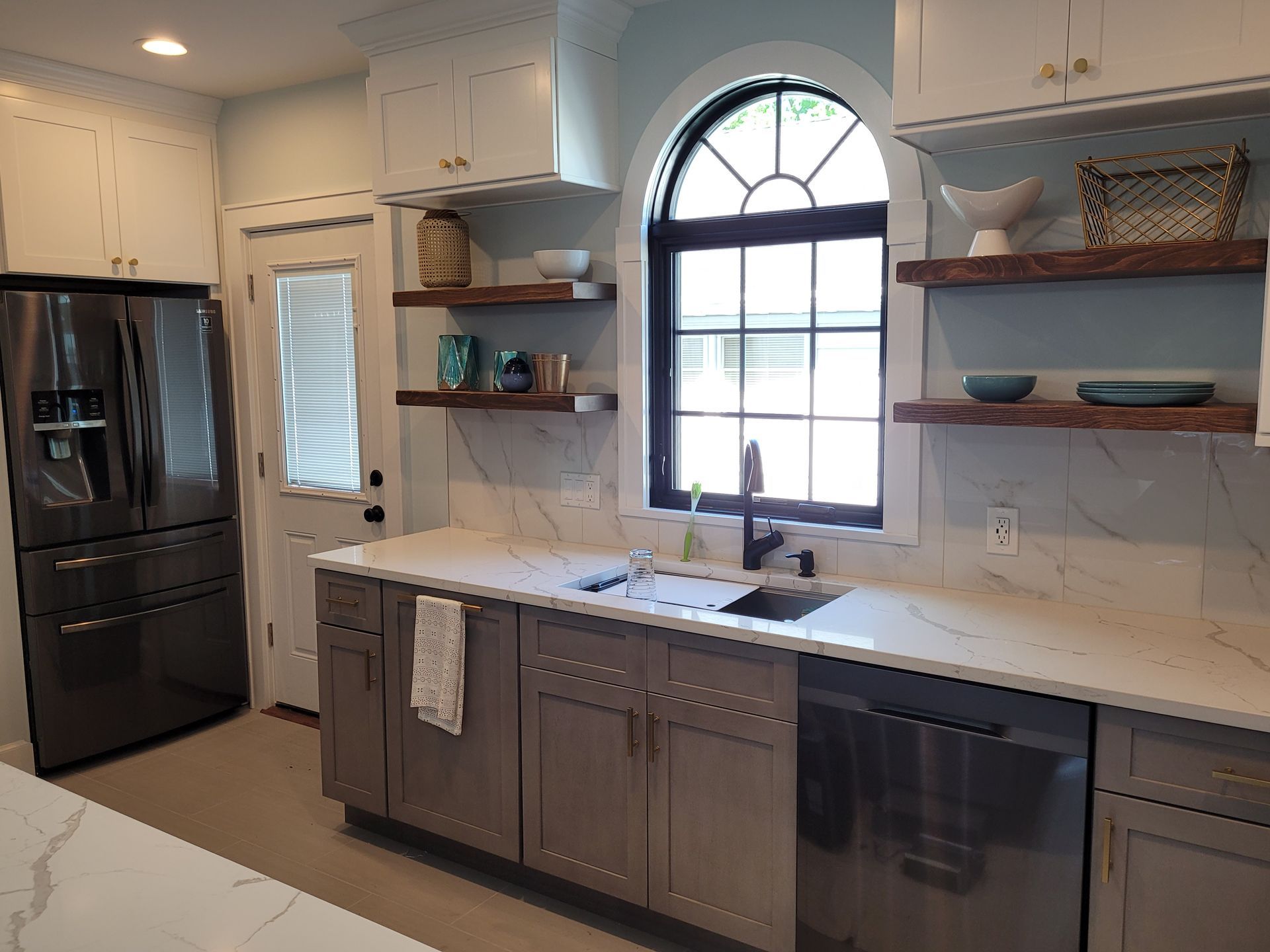 A kitchen with gray cabinets, white counter tops, stainless steel appliances and a large window.