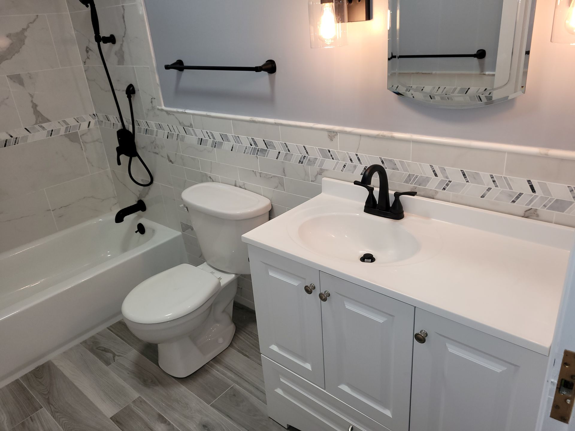A bathroom with a toilet, sink, bathtub and mirror.