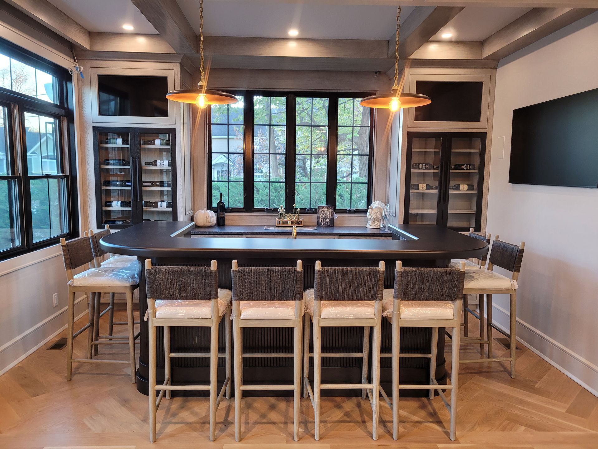 A kitchen with a large island and stools and a flat screen tv.