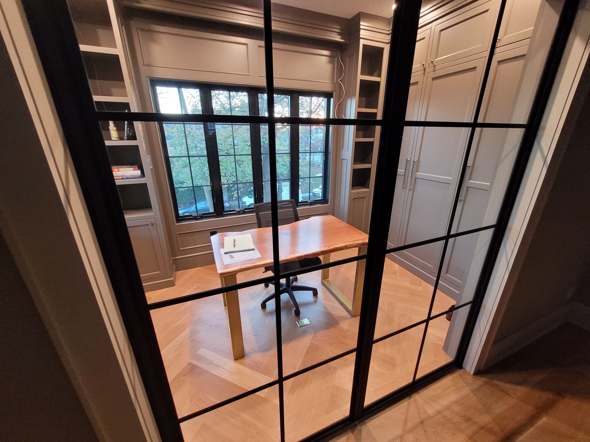 A home office with a desk and chair in front of a window.