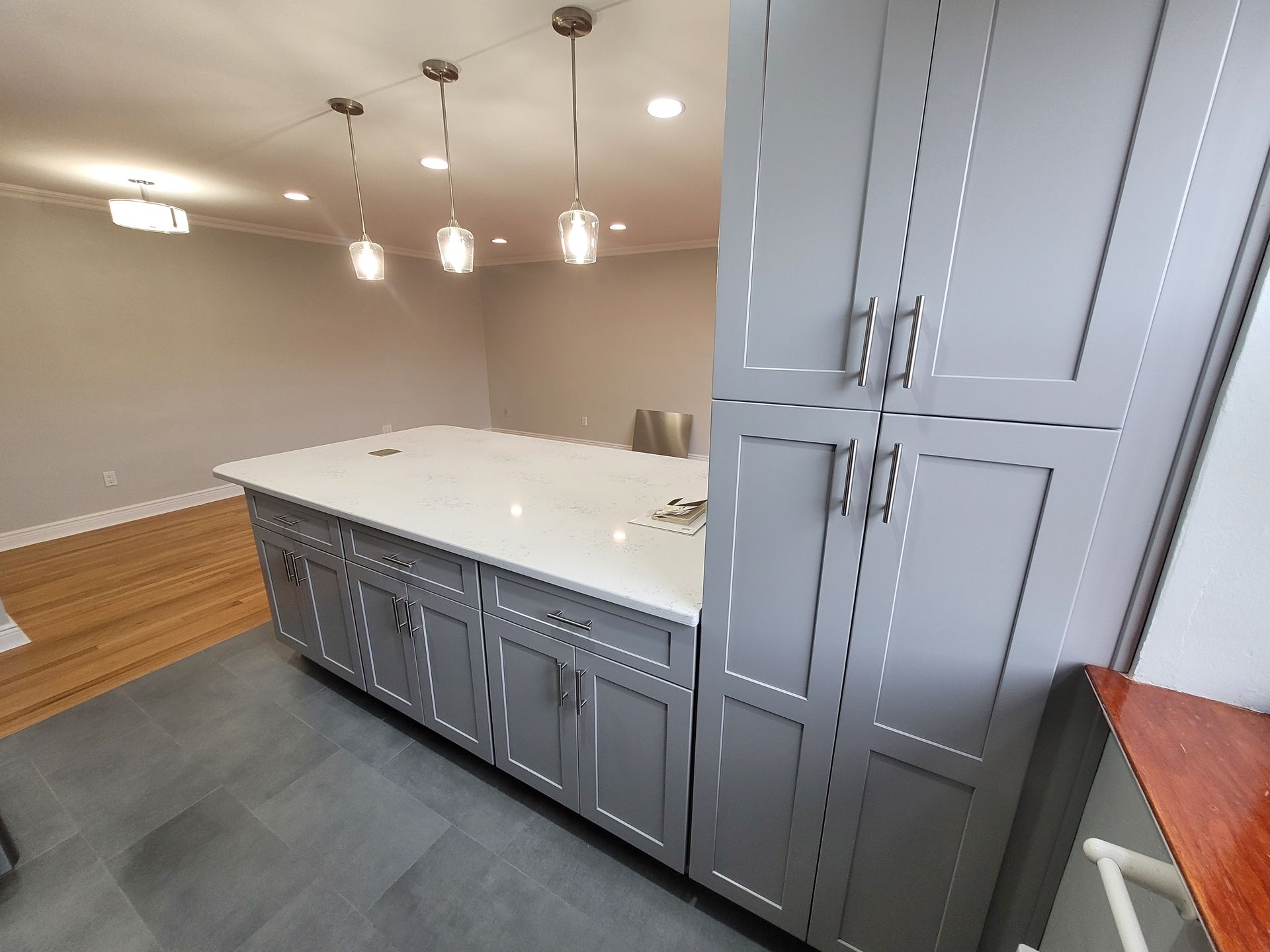 A kitchen with gray cabinets and white counter tops