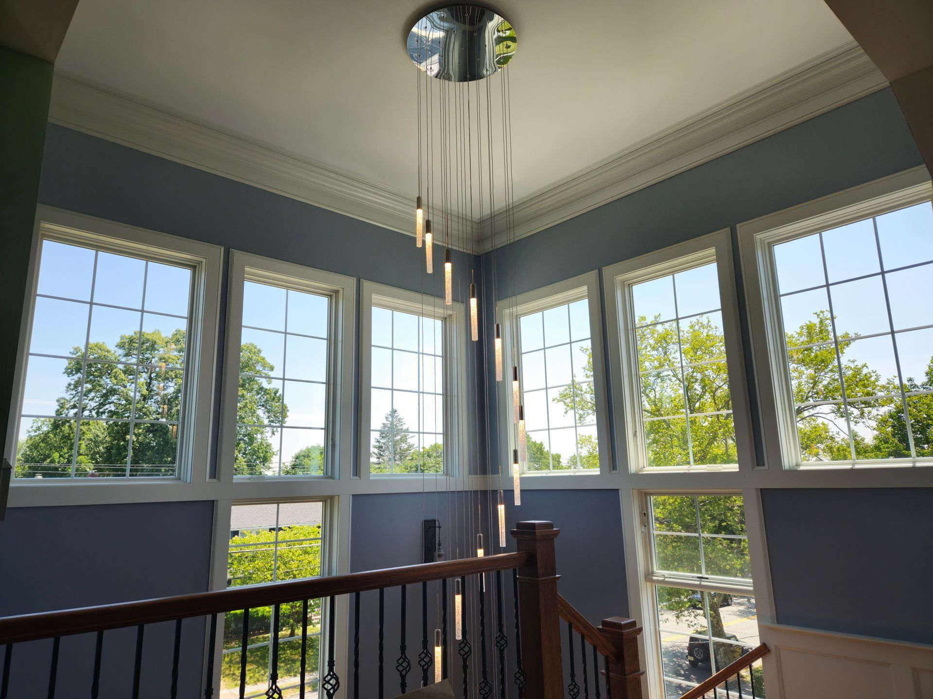 A large chandelier is hanging from the ceiling of a room with lots of windows.