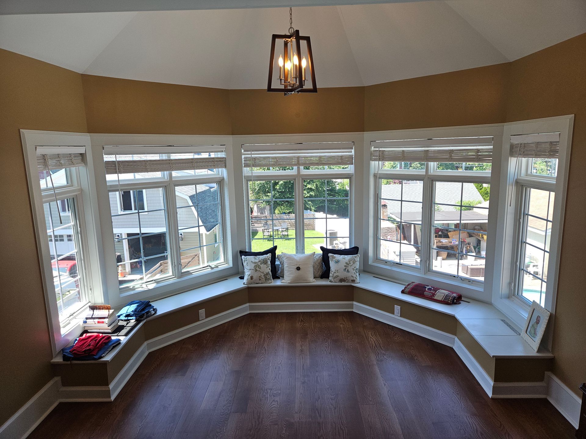 A living room with a large bay window and a chandelier hanging from the ceiling.
