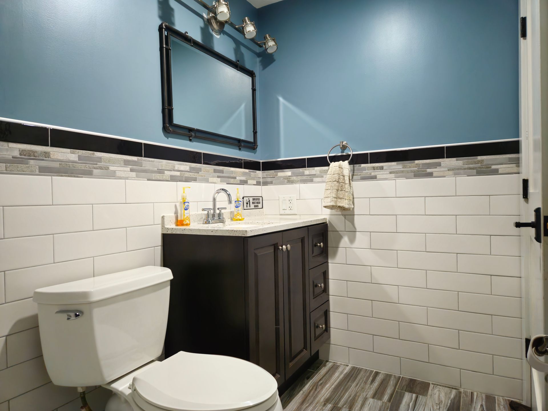 A bathroom with a toilet, sink and mirror.