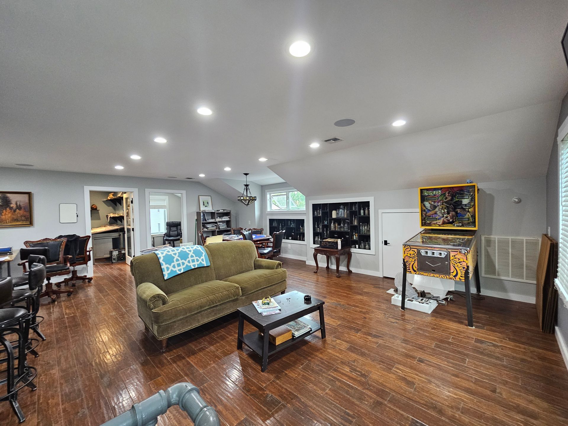 A living room with a couch, table, and pinball machine.