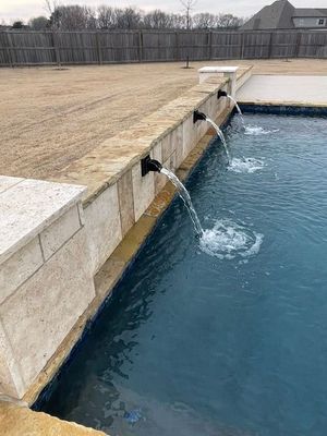 Pool with water flowing from three spouts into the water.