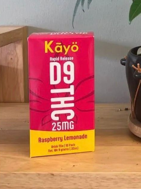 A box of Kayo Raspberry Lemonade drink mix containing 25mg of D9 THC, sitting on a wooden surface.