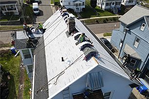 A group of people are working on the roof of a house.