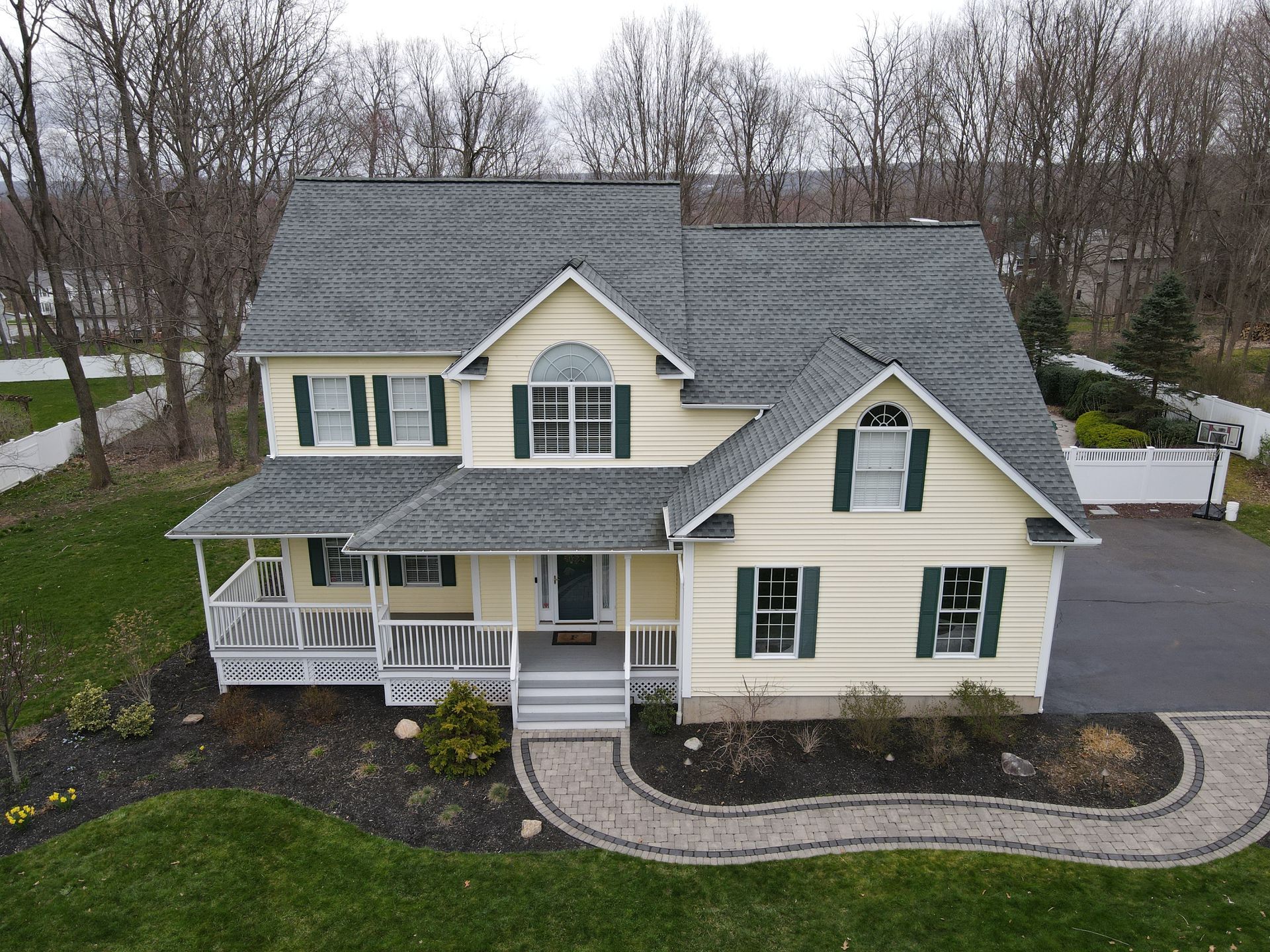 An aerial view of a house with a gray roof and green shutters
