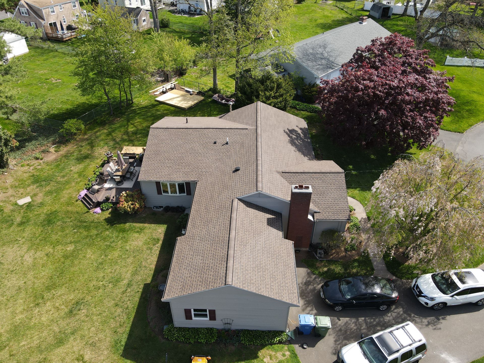 An aerial view of a house in a residential area with cars parked in front of it.