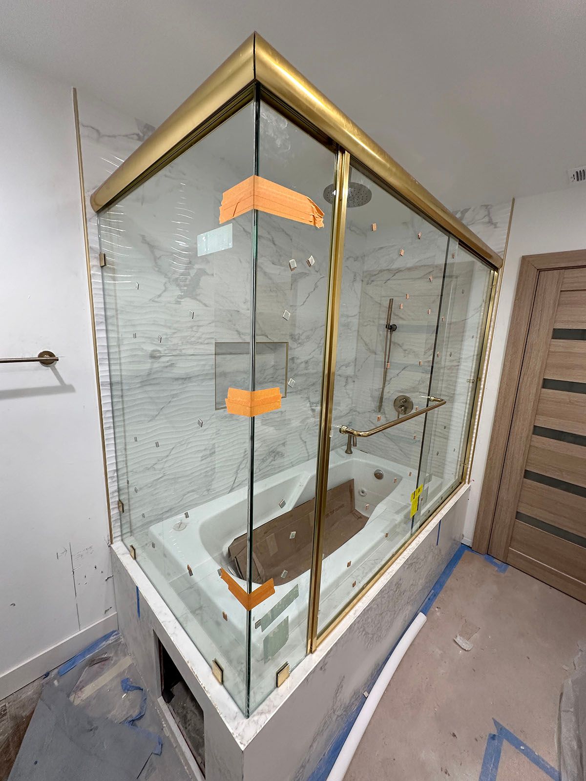 Modern glass shower enclosure with gold trim