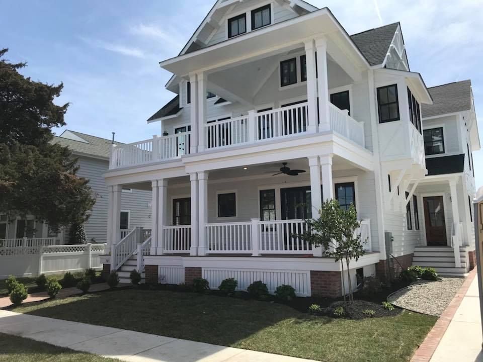 A large white house with a large porch and stairs.