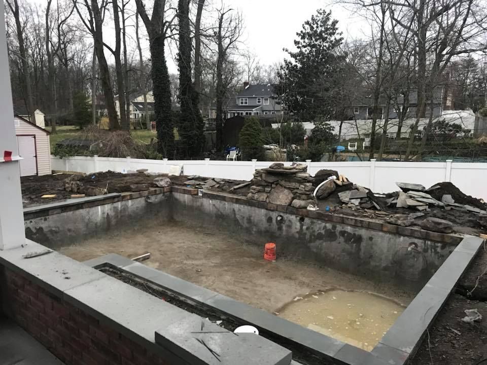 An empty swimming pool with a white fence in the background.