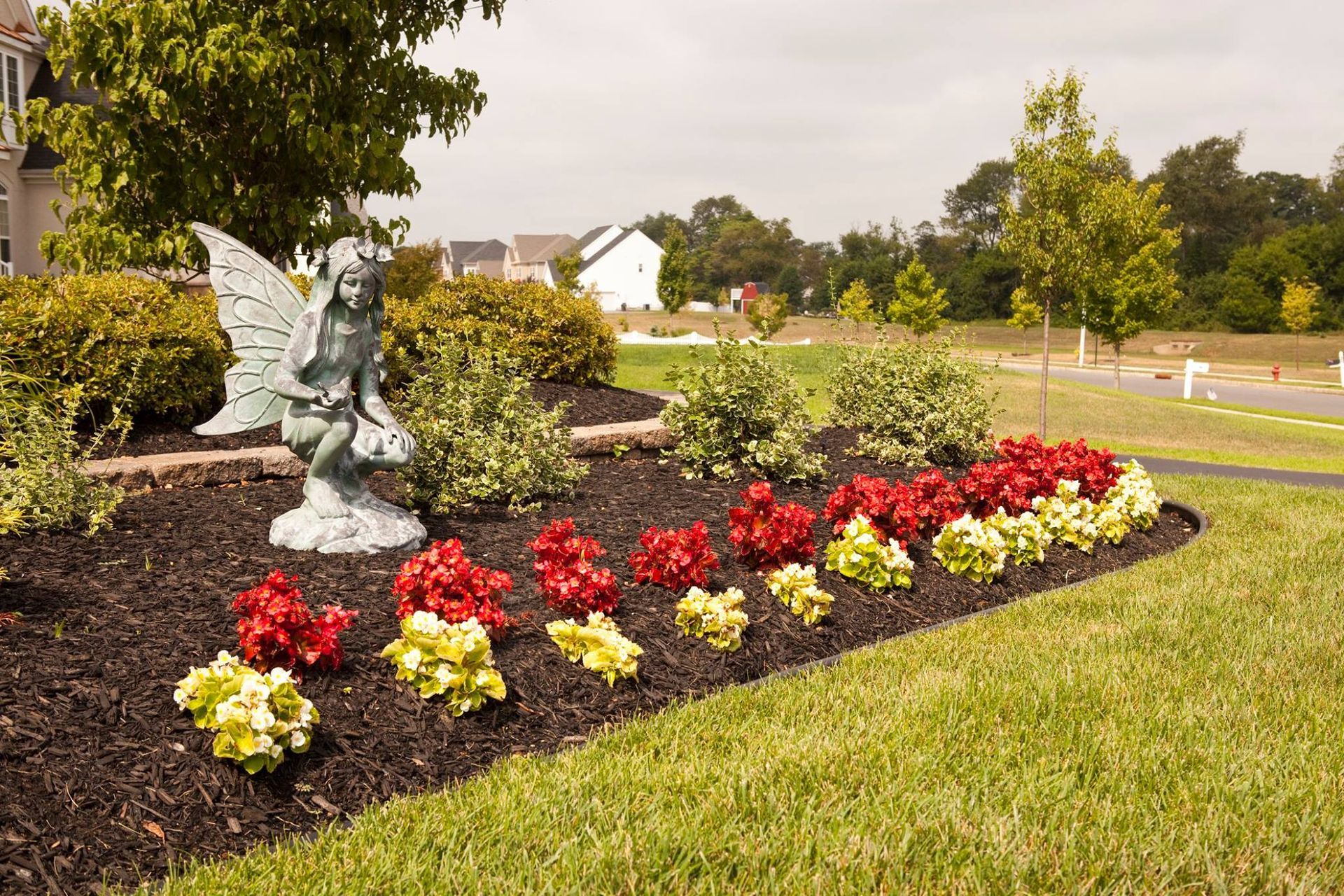 A garden with flowers and a statue of a fairy