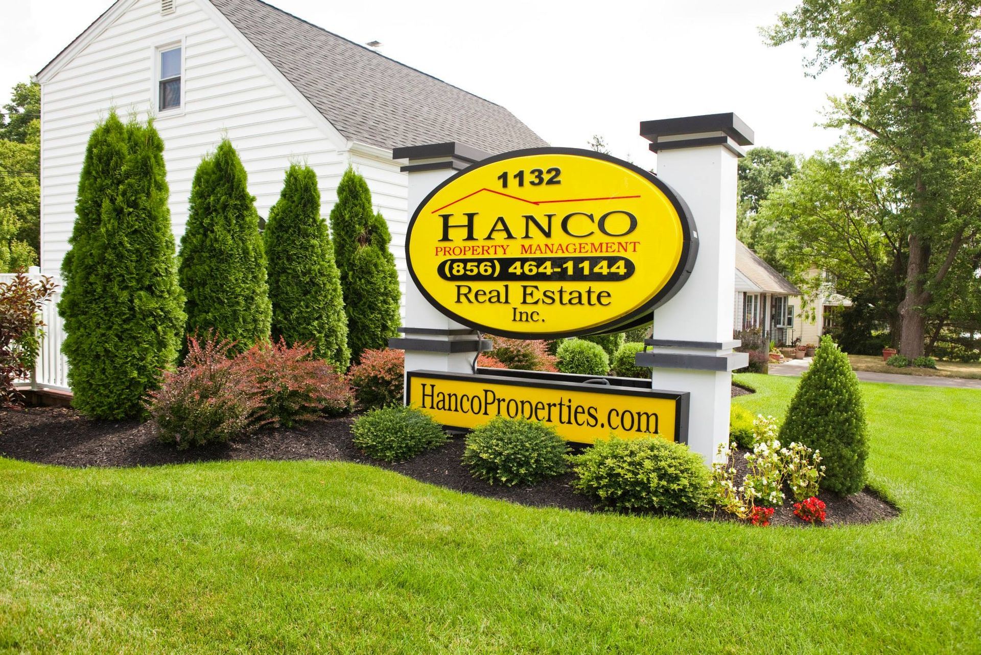A sign for hanco real estate in front of a house