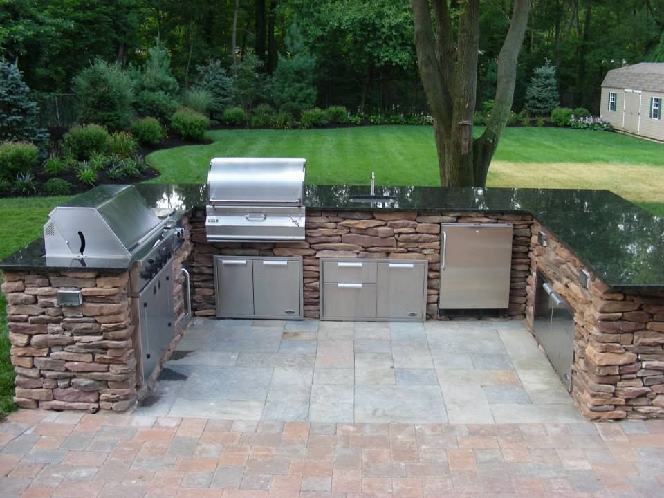 A large outdoor kitchen with a grill and a sink