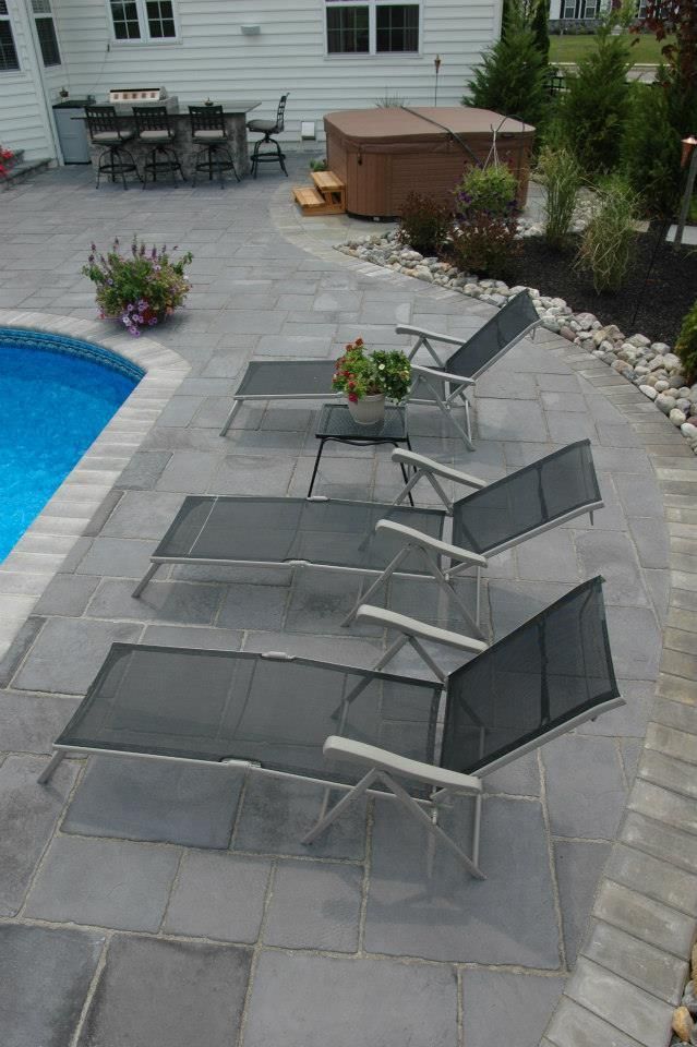 A row of lounge chairs are sitting on a patio next to a pool.