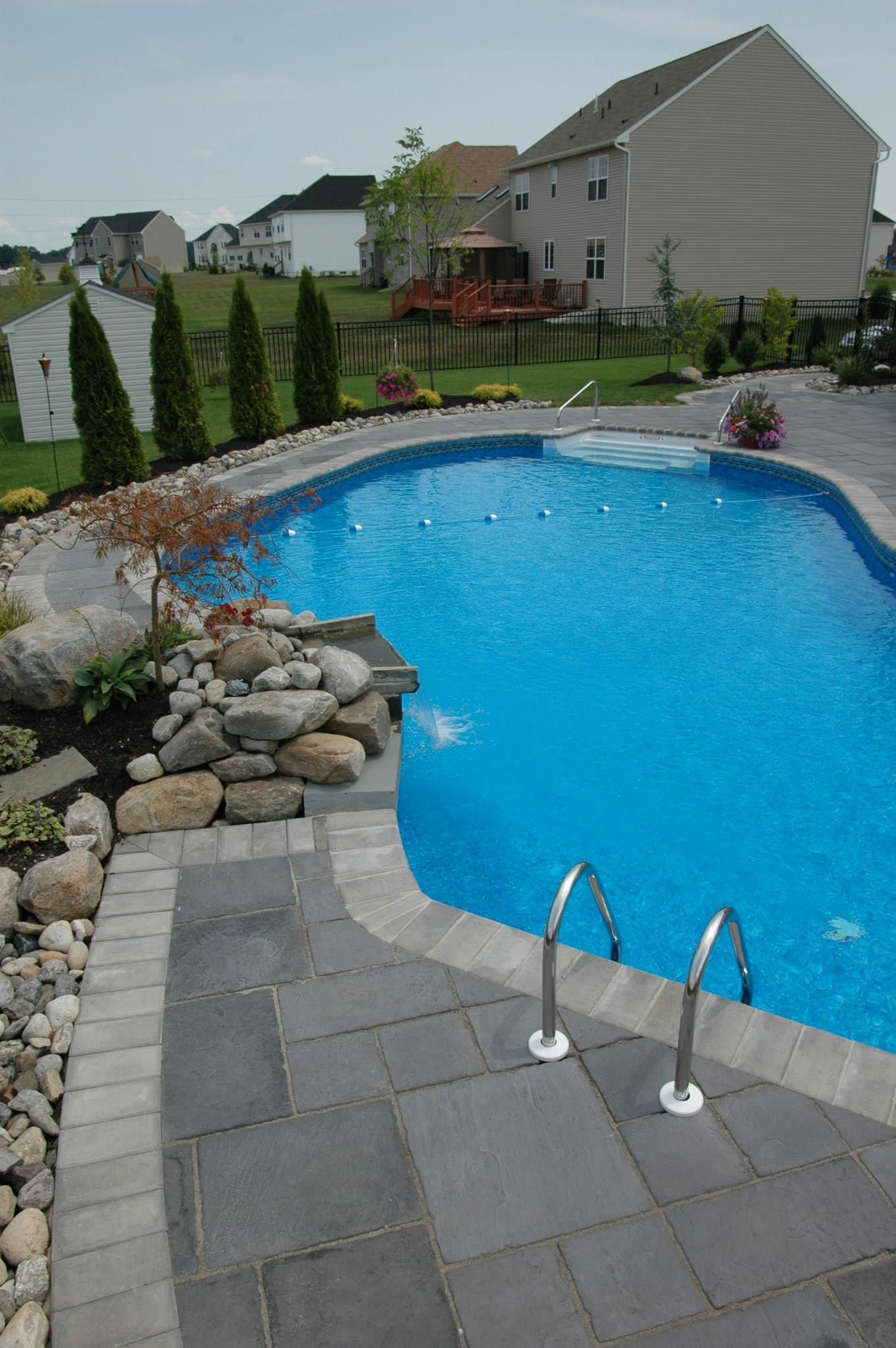A large swimming pool with a house in the background