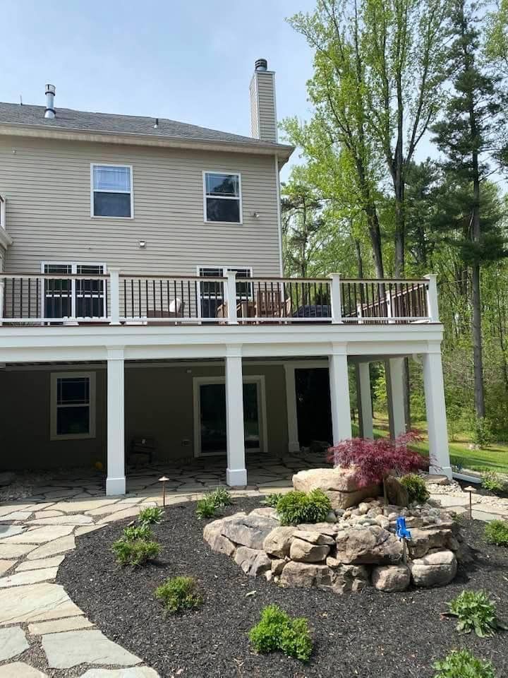 The back of a house with a large deck surrounded by trees