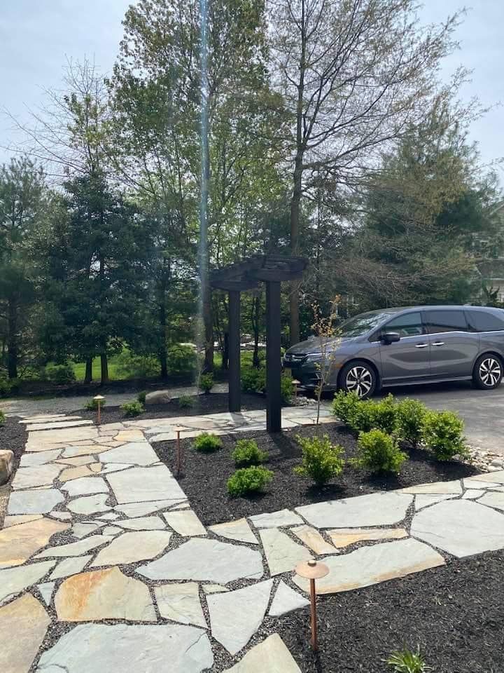A minivan is parked in a driveway next to a stone walkway.