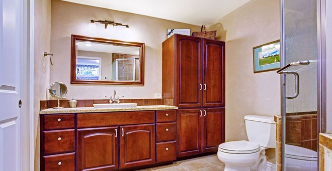 Bathroom with wooden vanity, large mirror, toilet, and glass shower enclosure.