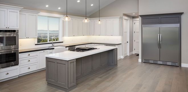 Bright modern kitchen with white cabinets, gray island, and stainless steel refrigerator