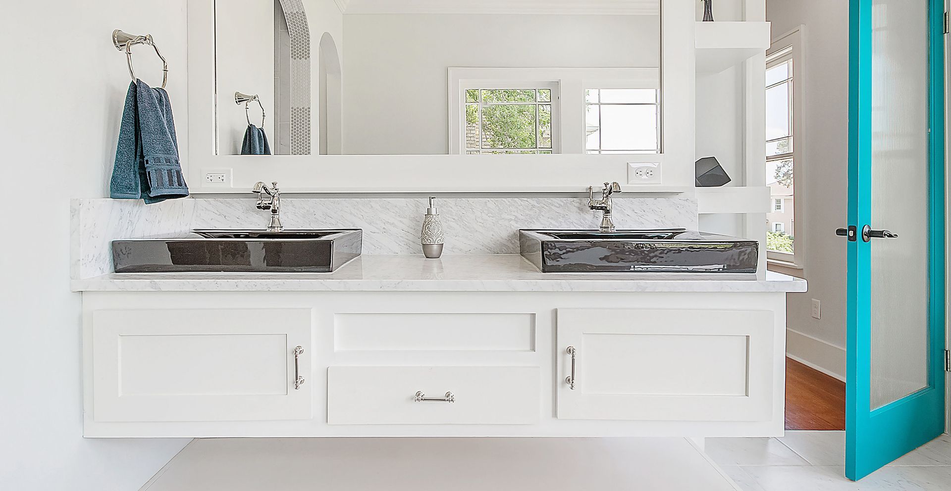 Modern white bathroom vanity with double sinks, mirror, and teal door accents
