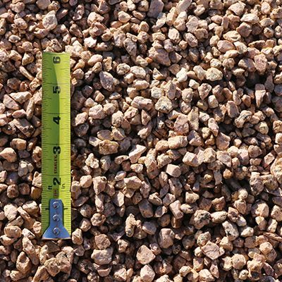 Tan gravel with a yellow tape measure for scale.