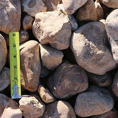 Brown and tan river rocks with a yellow measuring tape.