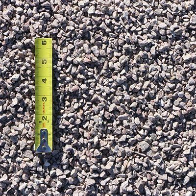Gravel stones with a measuring tape showing sizes; gray and tan colors.
