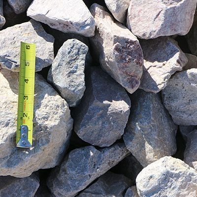 Pile of light gray rocks with a yellow and black measuring tape.