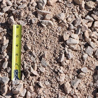 Gravel and sand mix with a yellow tape measure for scale.
