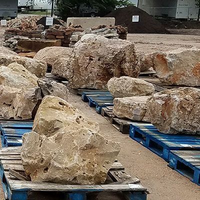 Large rocks on blue pallets at an outdoor landscaping supply store.