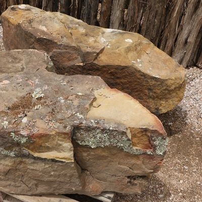 Two large, rough brown and tan rocks, with lichen, on gravel.
