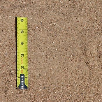 Tan sand with a yellow measuring tape next to it.