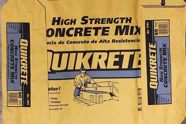 Yellow bag of QUIKRETE High Strength Concrete Mix. Illustration of a man working with cement.